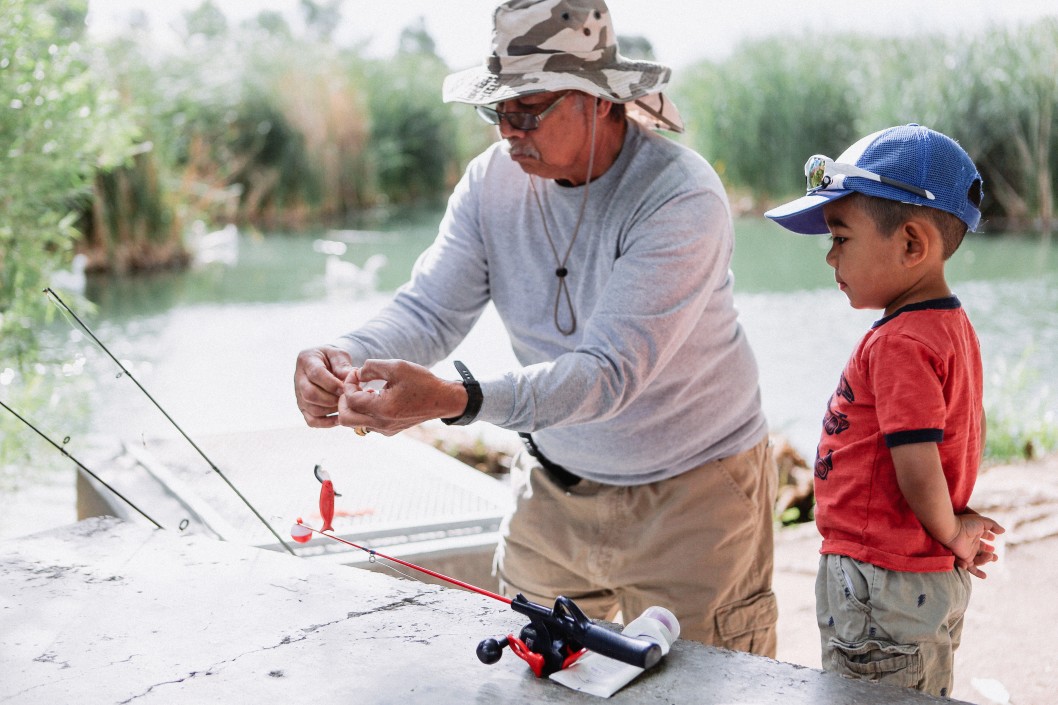 baby-boomer-grandparent-teaching-his-grandson-how-to-fish-at-a-local-lake