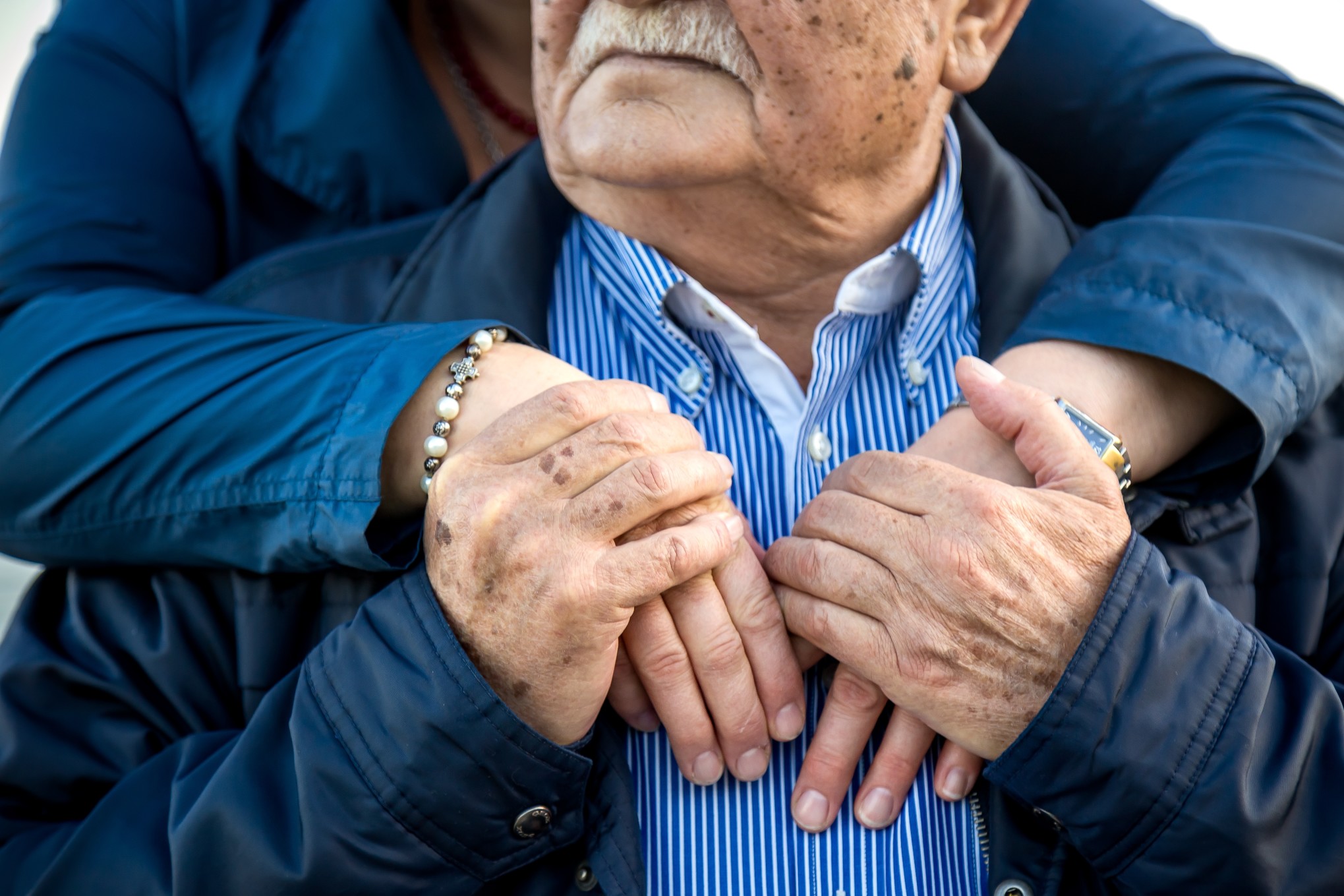 close-up-two-older-people-hugging-holding-hands