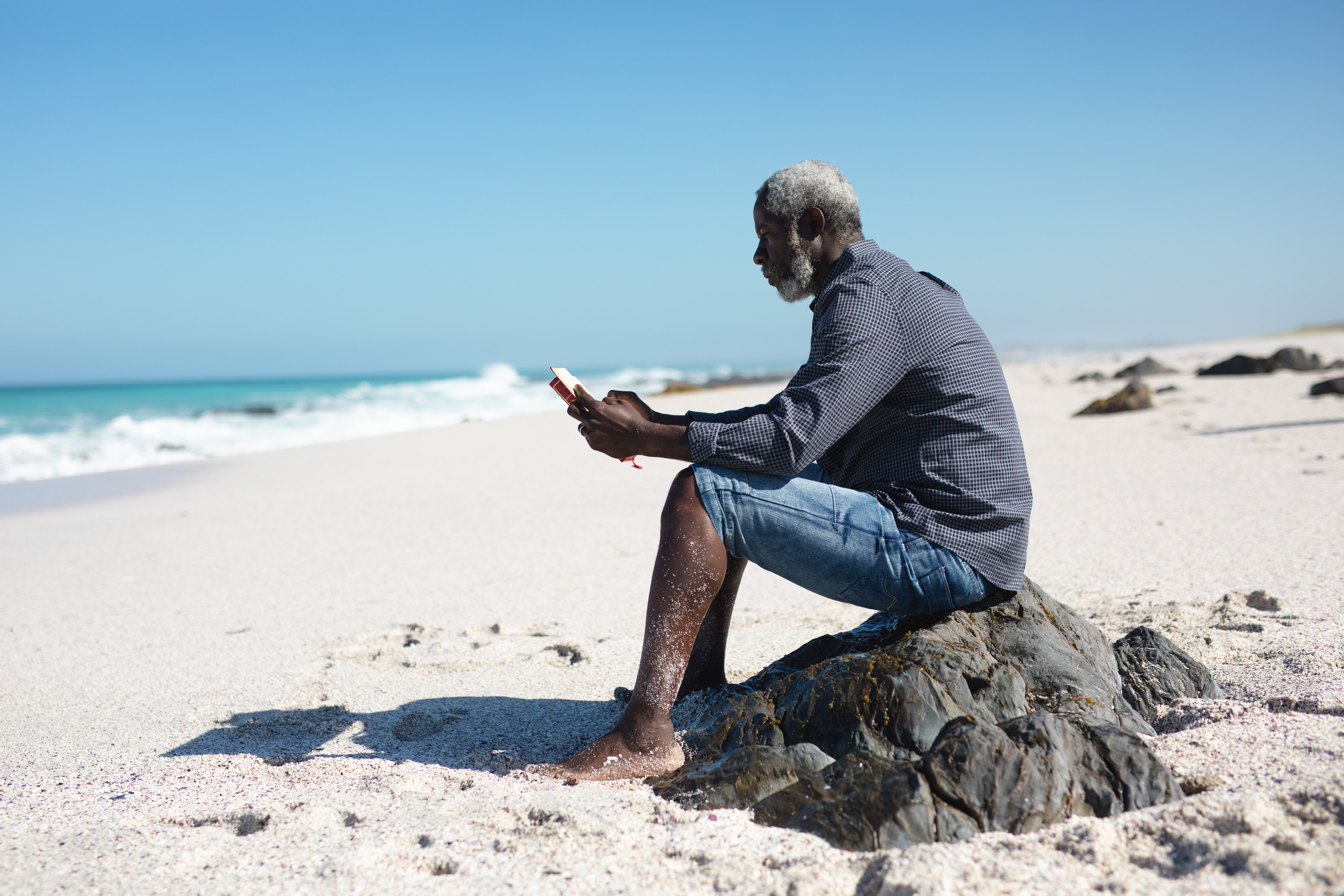 old-man-reading-book-at-the-beach-QC4R36V