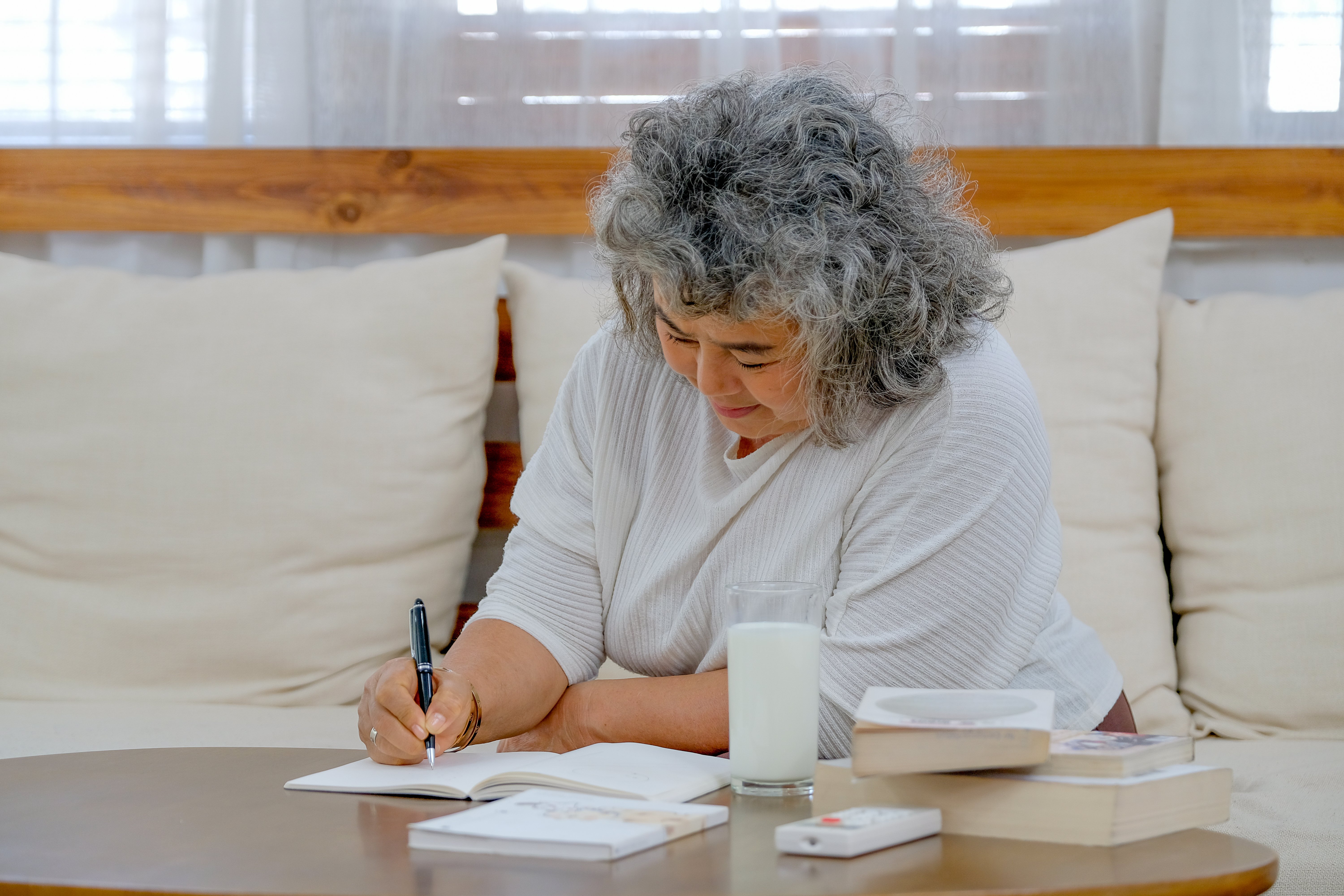 older-woman-use-pen-to-write-into-notebook