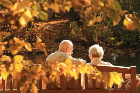 senior-couple-sitting-on-bench-during-fall