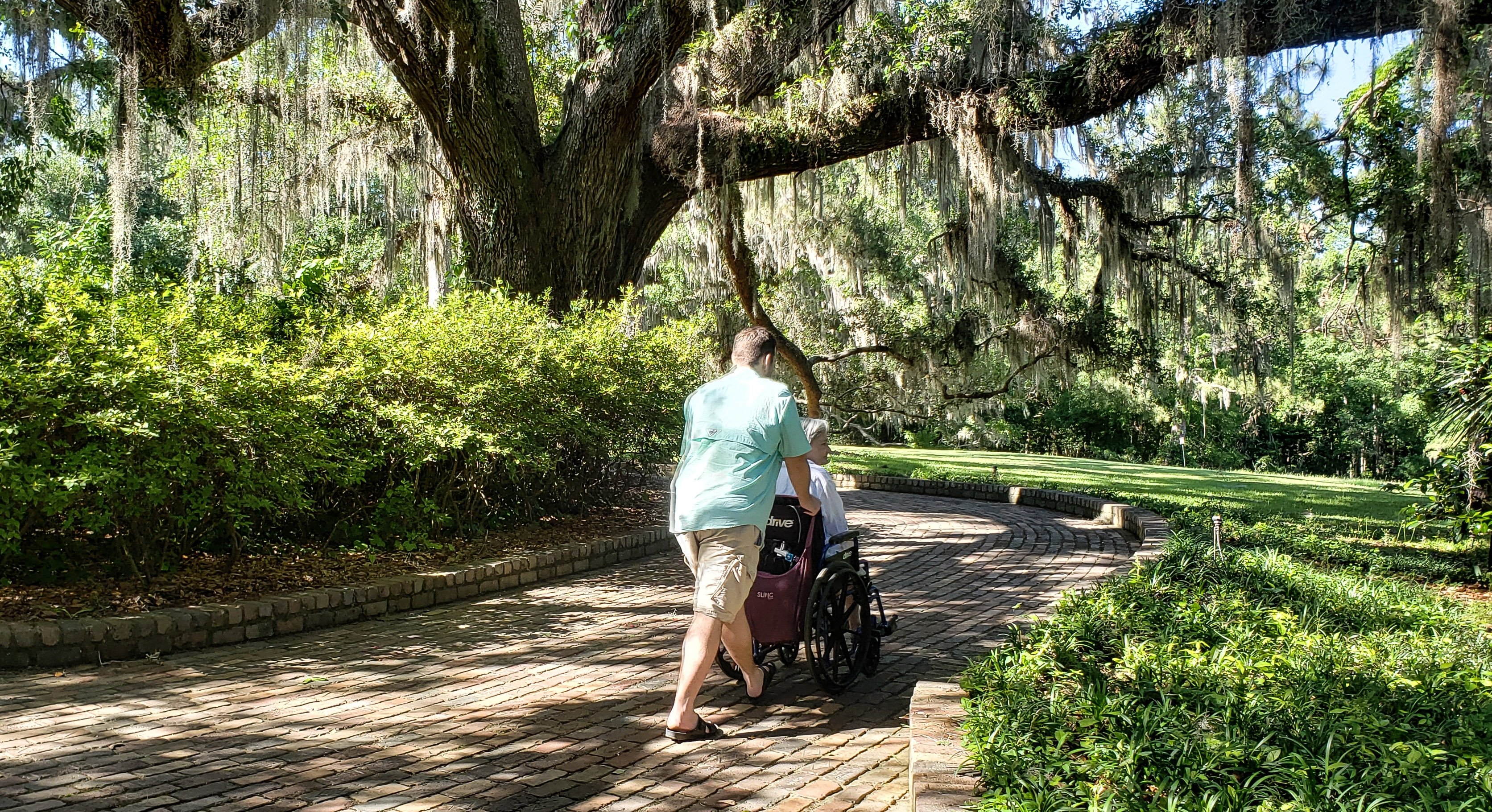 senior-citizen-in-a-wheelchair-being-pushed-through-a-brick-pathway