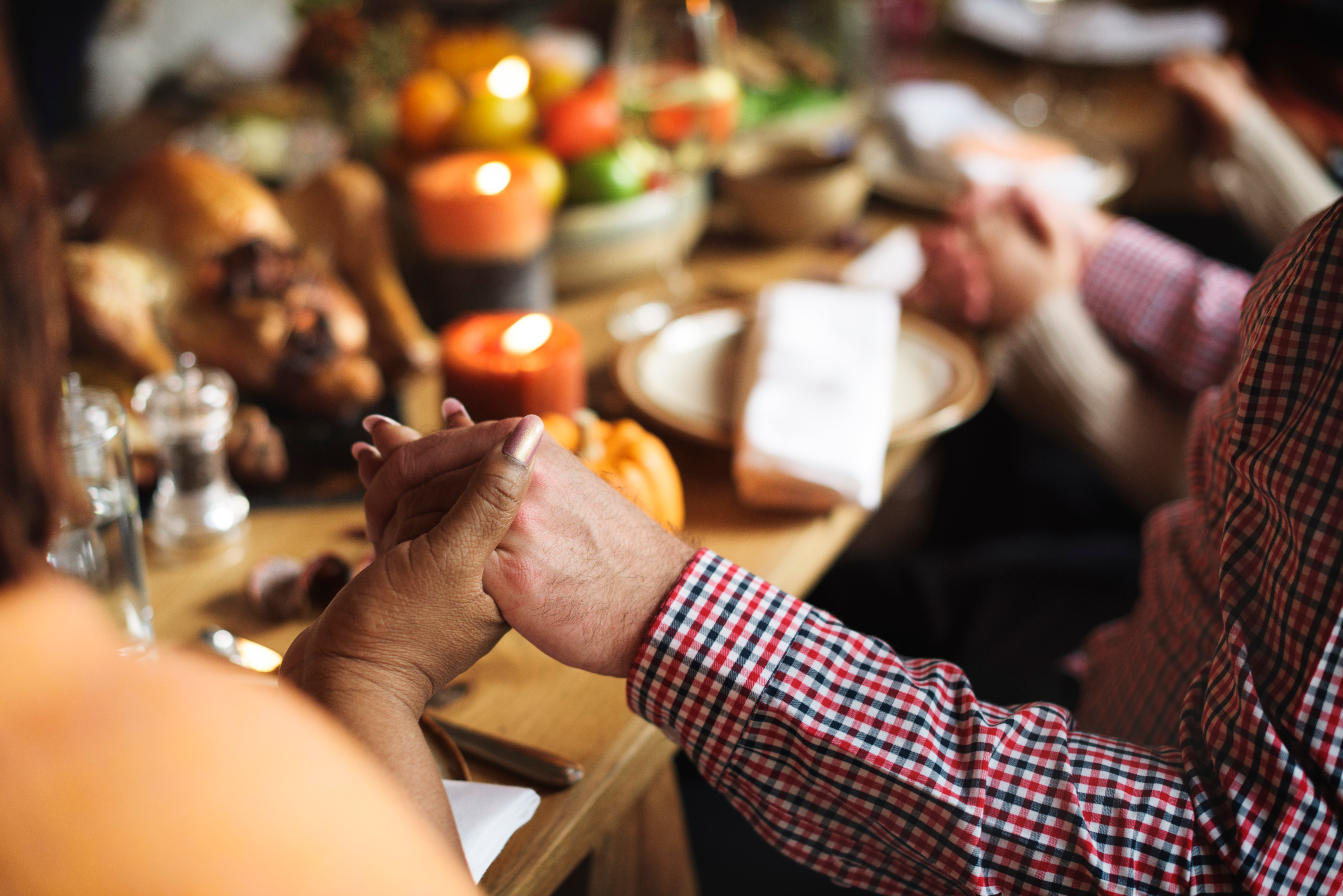 close-up-family-holding-hands-around-thanksgiving-table