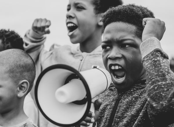 young-boy-shouting-on-a-megaphone-in-a-protest-L4ENM9F