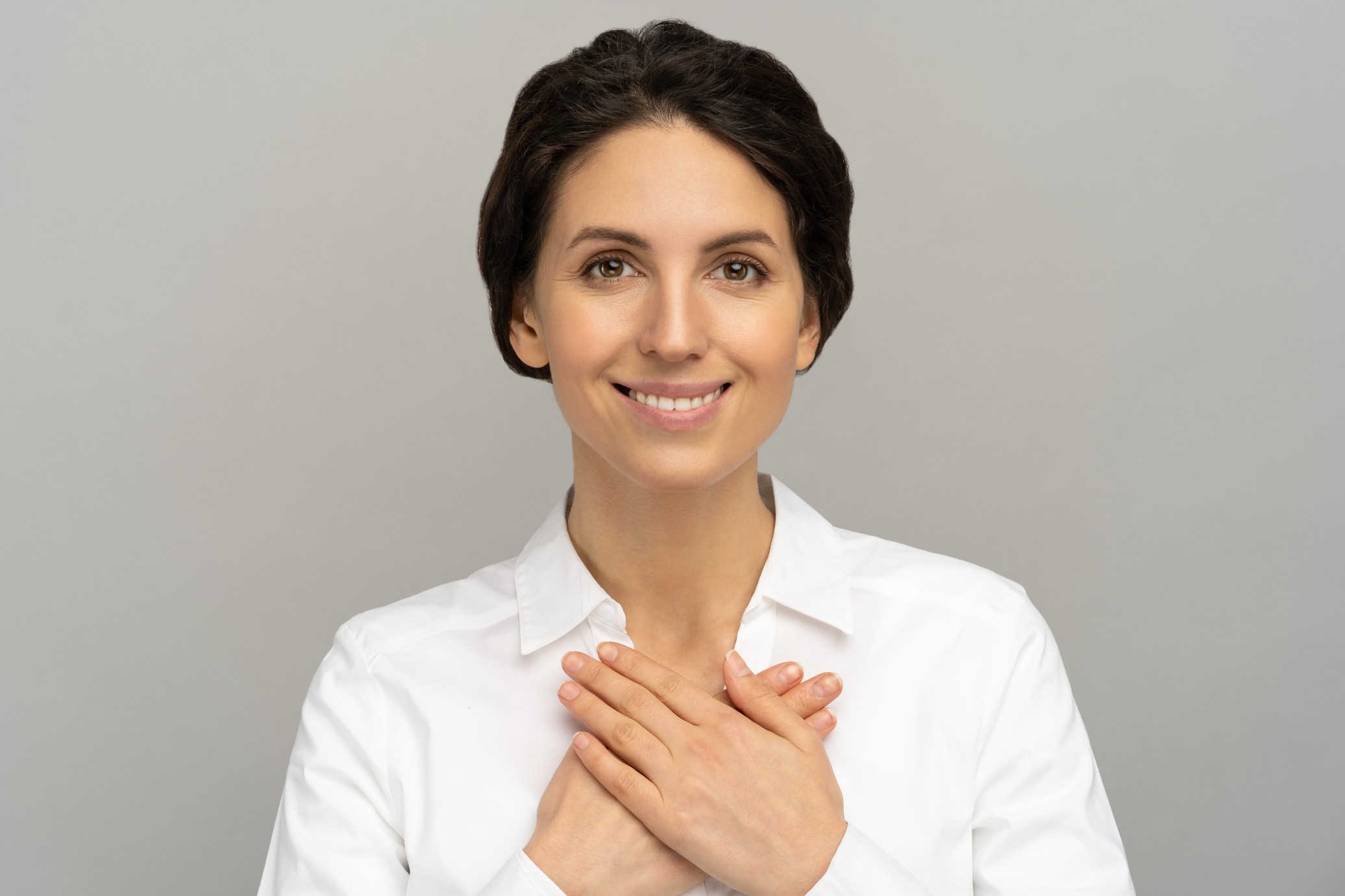 woman-smiling-with-both-hands-on-heart